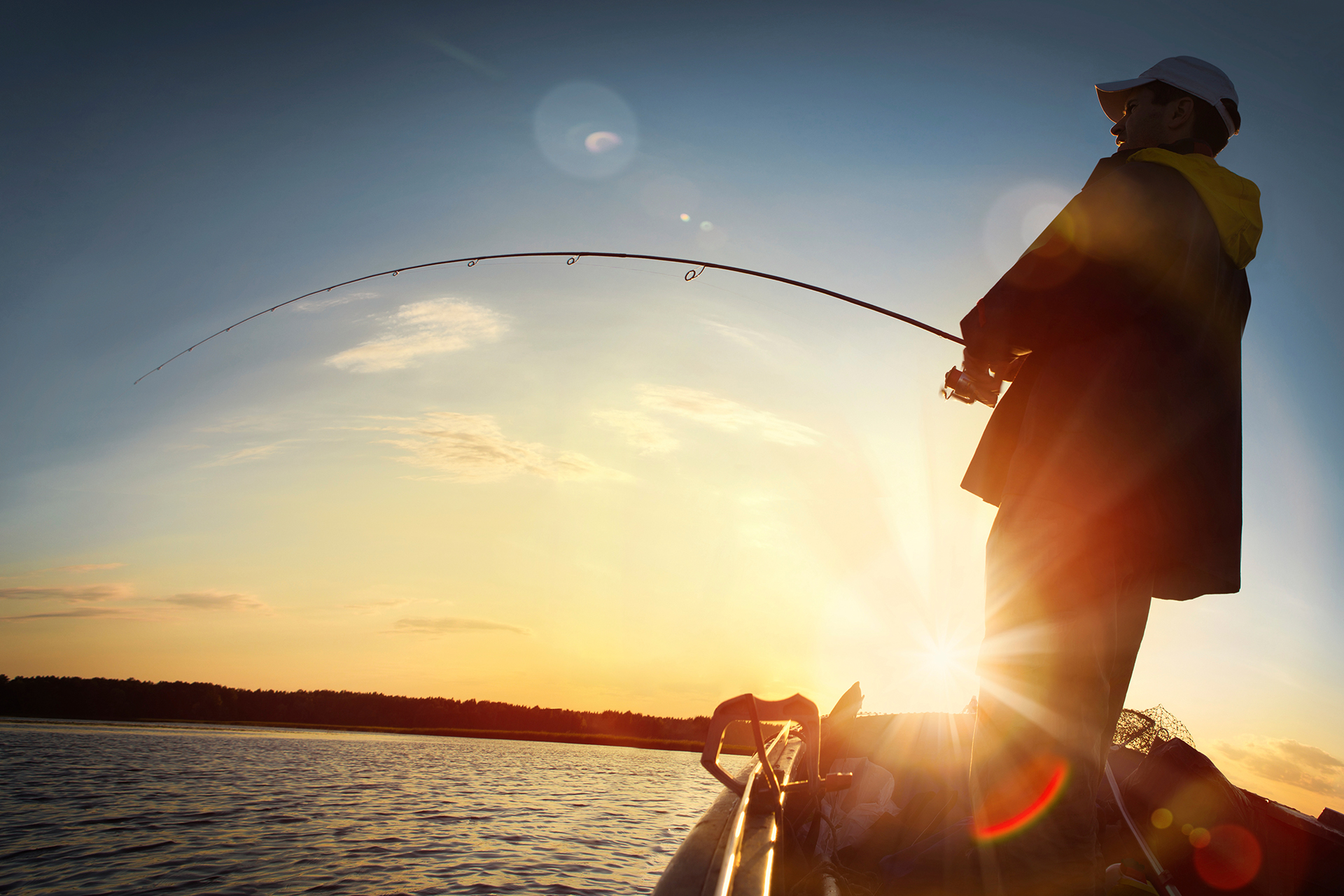 a fisherman at dusk reeling in a catch on a boat