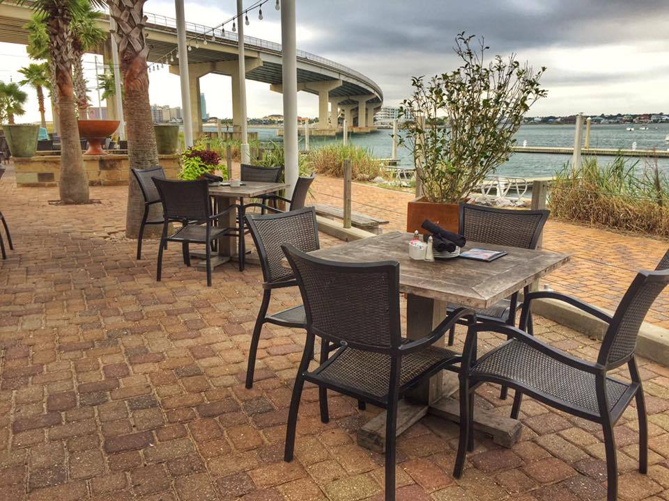 Cobalt the Restaurant outdoor seating area on the water, at the foot of a bridge.